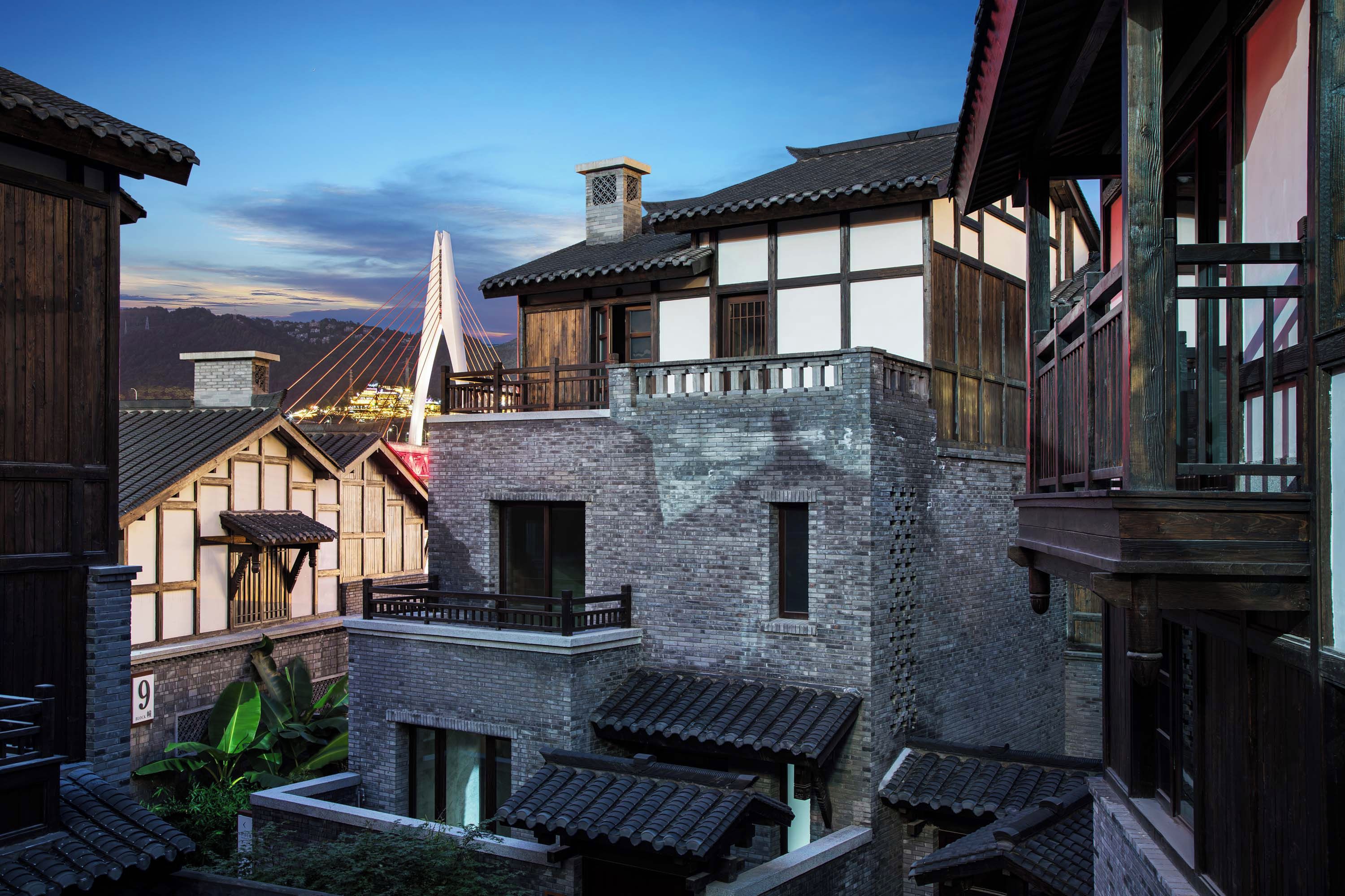 Un edificio tradicional con fachada de piedra, balcones de madera y una vista de un puente al fondo.