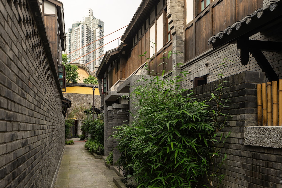 Une ruelle étroite aux bâtiments d’architecture traditionnelle, avec notamment des portes en bois et des murs en briques.