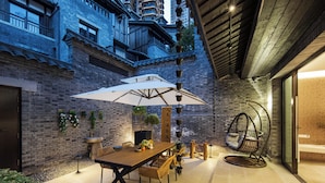 An outdoor patio with a wooden table and chairs, a hanging chair, and a large umbrella. - Daily Fortune  Tianshun River View Villa (Chongqing)
