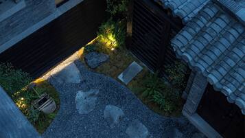 Un patio con pavimento de piedra, cerca de madera y plantas pequeñas.