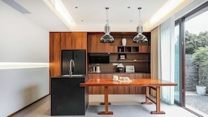 A modern kitchen with a wooden island, black appliances, and pendant lighting. - Daily Fortune  Tianshun River View Villa (Chongqing)