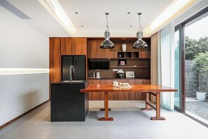 Une cuisine moderne avec un îlot central en bois, des appareils électroménagers noirs et des luminaires suspendus.