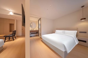 Une chambre d’hôtel moderne équipée d’un grand lit, d’un bureau, d’une chaise et d’un téléviseur.