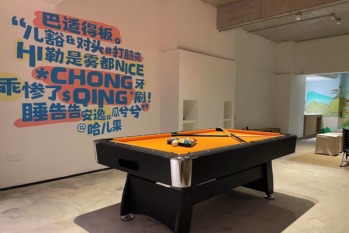 Une table de billard dans une pièce dont un mur est décoré d’un texte aux couleurs vives.
