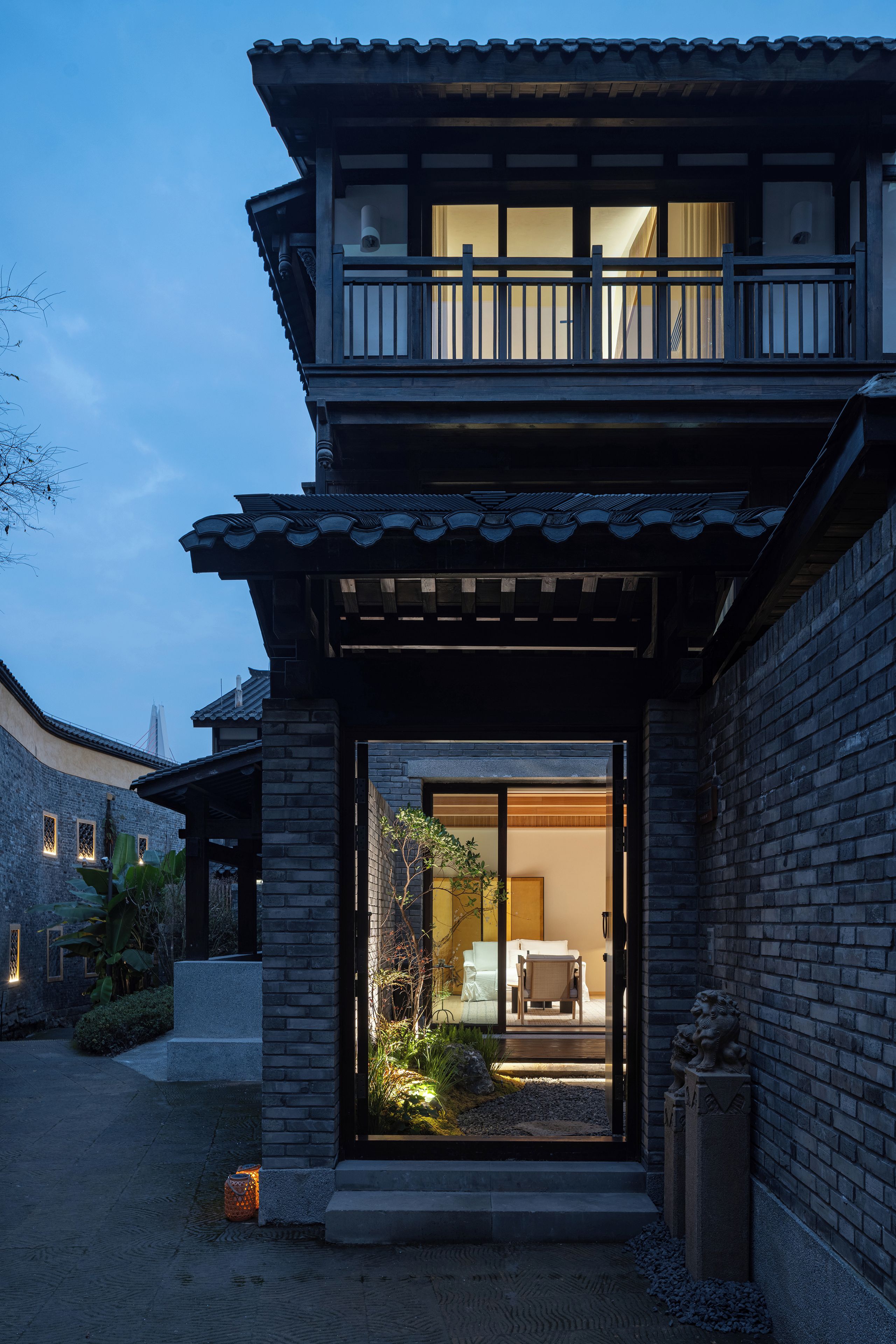 Una casa tradicional al estilo japonés con un balcón de madera, una entrada con puerta corredera de vidrio y un pequeño jardín.