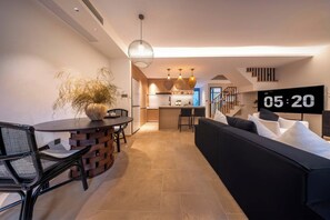 A modern living room with a black sofa, a dining table with chairs, and a kitchen area in the background. - Daily Fortune  Tianshun River View Villa (Chongqing)