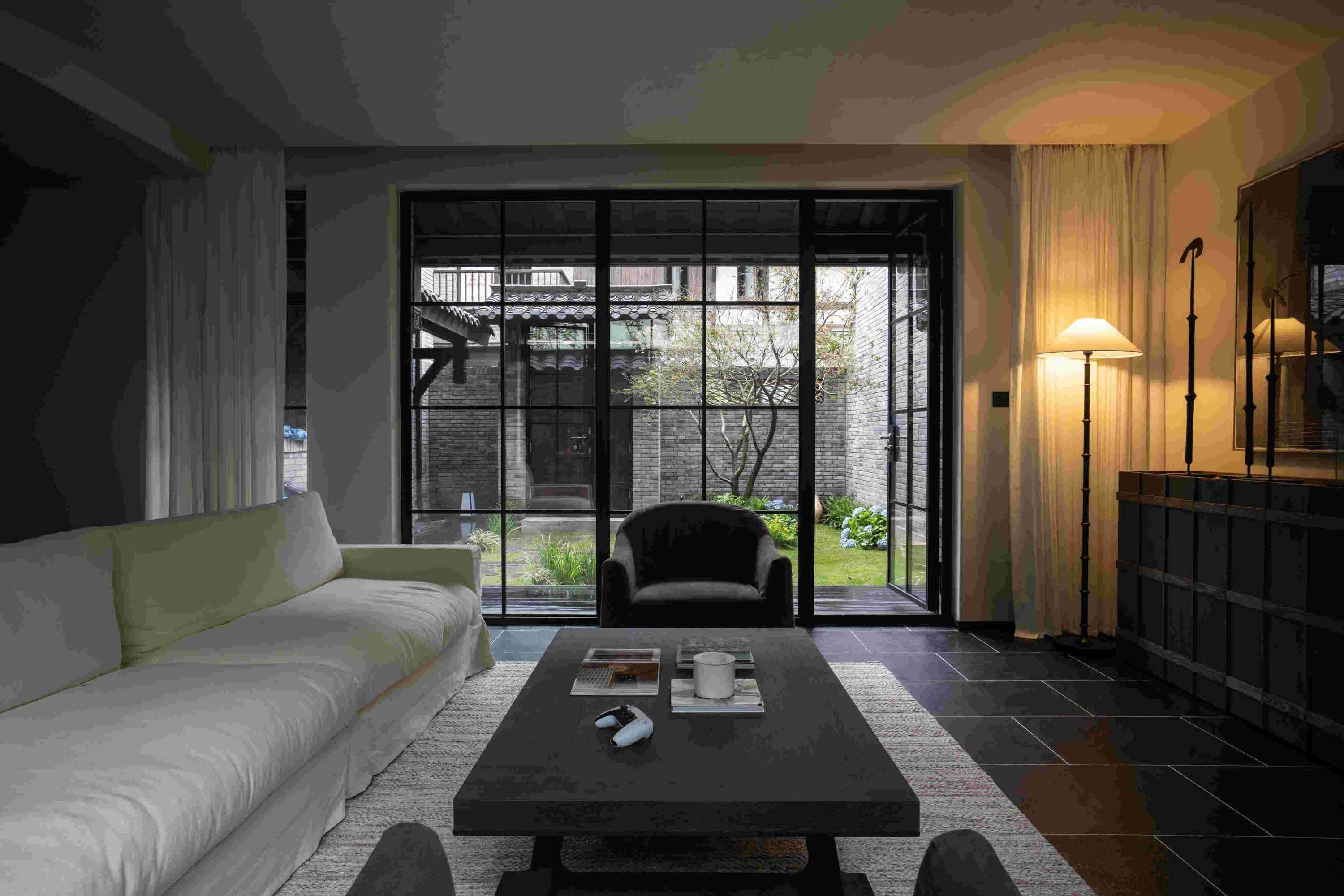 Una sala de estar moderna con un sofá, una mesa de centro y vistas a través de un gran ventanal corredero.