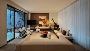 A modern living room with a large sofa, a coffee table, and a television. There is a large window with a view of a brick wall and a hanging chair outside. - Daily Fortune  Tianshun River View Villa (Chongqing)