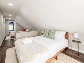 Ein Schlafzimmer mit einem großen Bett, einem Nachttisch, einer Lampe und Blick ins Bad.