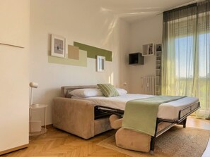 A modern bedroom with a bed, bedside tables, a radiator, and a window with curtains. - The Washington Studio Apartment - Balcony (Milan)