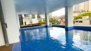 A swimming pool with clear blue water, surrounded by a tiled deck and white walls. - Charming apartment in beautiful Kilimani, Nairobi perfect for your stay (Nairobi)