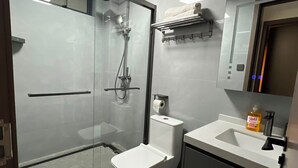 A modern bathroom with a glass-enclosed shower, a toilet, a sink with a soap dispenser, and a mirror above the sink. - Charming apartment in beautiful Kilimani, Nairobi perfect for your stay (Nairobi)