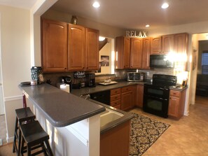 A kitchen with wooden cabinets, a microwave, a toaster, and a coffee maker. - Lovely townhome in the popular Villages of Five Points (Lewes)