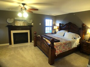 A bedroom with a large bed, a fireplace, and a ceiling fan. - Lovely townhome in the popular Villages of Five Points (Lewes)