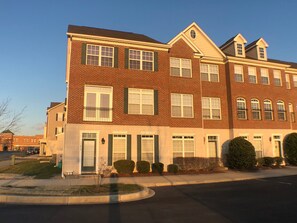 A multi-story brick building with a symmetrical facade, multiple windows, and a central entrance. - Lovely townhome in the popular Villages of Five Points (Lewes)