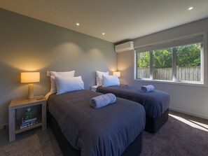 A hotel room with two beds, a window, and a nightstand with a lamp. - Beachside Bliss - Two Bedroom Apartment (Napier)