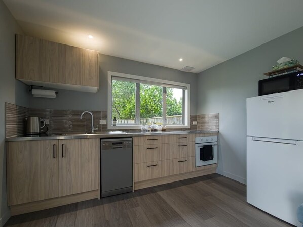 A modern kitchen with wooden cabinets, stainless steel appliances, and a window providing natural light.