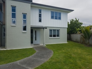 A two-story residential building with a paved driveway and a well-maintained lawn.
