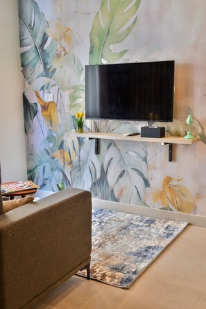 A living room with a flat-screen TV mounted on a wooden shelf, a brown sofa, and a patterned rug. - Luxury stay at Degla by Spacey #66 (Cairo)