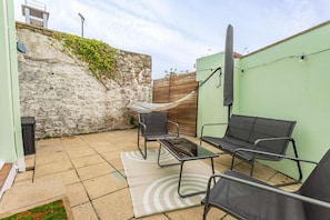 A patio with a hammock, two chairs, a table, and a solar-powered light fixture. - 5 West -2 Bedroom House - Tenby (Tenby)