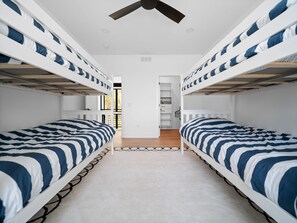 Ein Zimmer mit Etagenbetten, einer zentralen Tür und Blick auf einen Balkon.