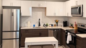 A modern kitchen with white cabinets, stainless steel appliances, and a central island. - Enjoyable apartment at Dallas neighborhood (Dallas)