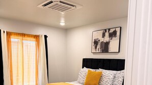 A bedroom with a bed, a headboard, a window with curtains, a ceiling vent, and a wall-mounted artwork. - Enjoyable apartment at Dallas neighborhood (Dallas)