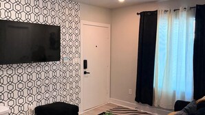 A modern living room with a flat-screen TV mounted on the wall, a black sofa, a small black coffee table, and a zebra-patterned rug. - Enjoyable apartment at Dallas neighborhood (Dallas)