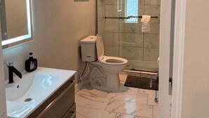 A bathroom with a glass-enclosed shower, a white toilet, and a vanity with a mirror. - Enjoyable apartment at Dallas neighborhood (Dallas)