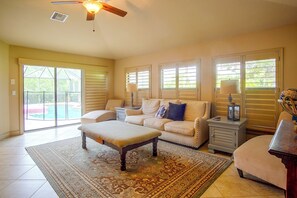A spacious living room with a large window, a ceiling fan, and a pool visible through the glass doors. - Private Yard w/ Fire Pit & Pool! Cape Coral Escape (Cape Coral)