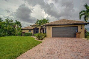 A two-story house with a tiled roof, a garage, and a well-maintained lawn. - Private Yard w/ Fire Pit & Pool! Cape Coral Escape (Cape Coral)