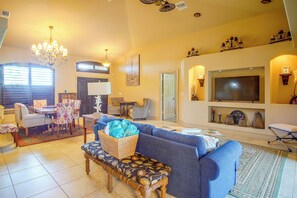 A living room with a sofa, a bench, a TV, and a chandelier. - Private Yard w/ Fire Pit & Pool! Cape Coral Escape (Cape Coral)