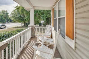 A covered porch with white wooden chairs and a view of a road and greenery. - Easy Access to 12 South! Nashville Home (Nashville)