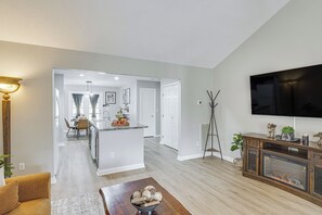 A modern living room with a flat-screen TV, a fireplace, and a dining area with a kitchen in the background. - Easy Access to 12 South! Nashville Home (Nashville)