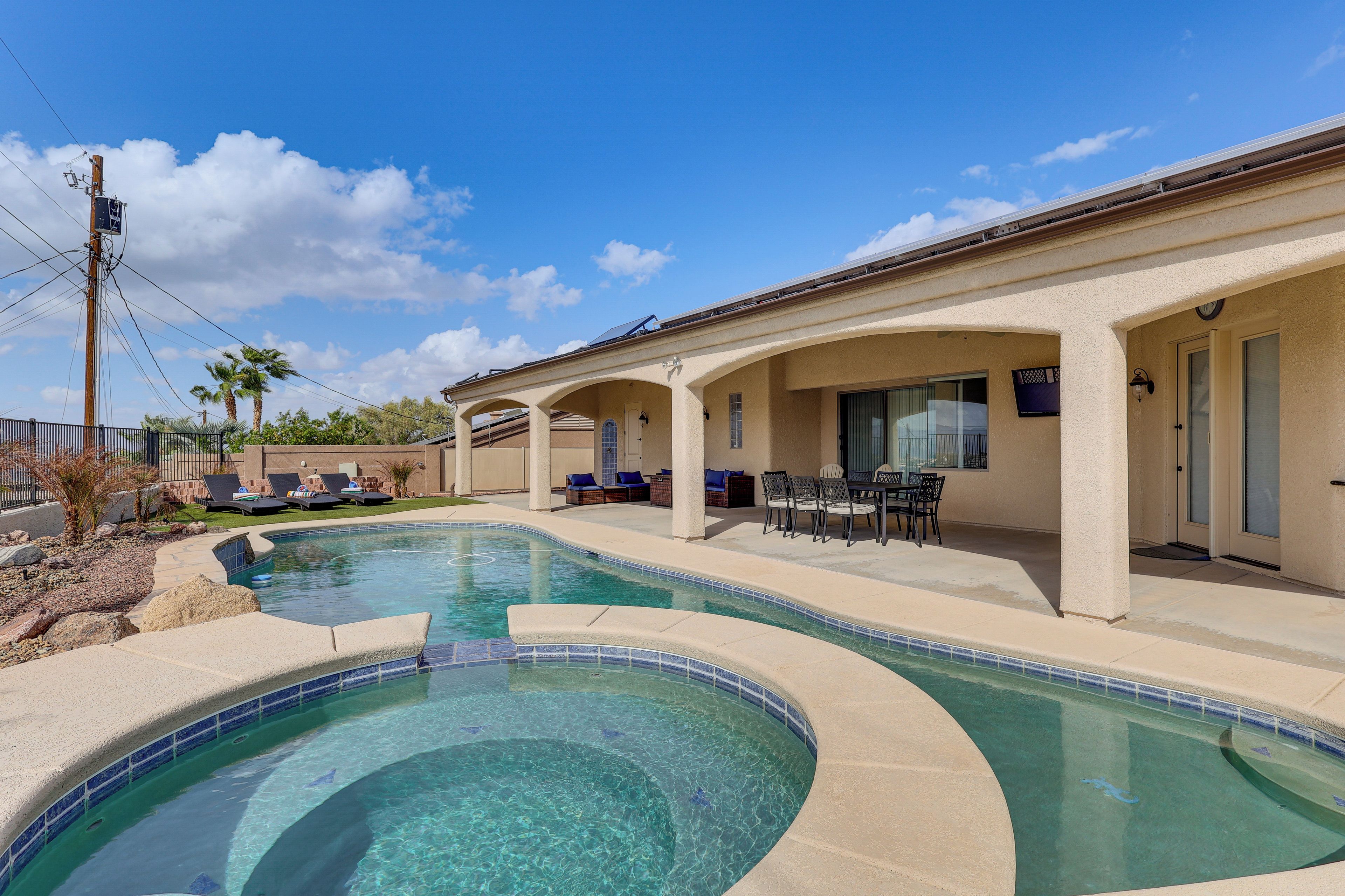 A pool area with a curved design, outdoor seating, and a covered patio.
