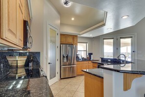 A modern kitchen with a stainless steel refrigerator, wooden cabinets, and a black marble countertop. - Mtn Views, Hot Tub! Extended Lake Havasu Escape (Lake Havasu City)