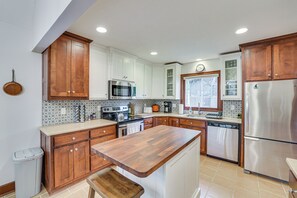 A kitchen with wooden cabinets, stainless steel appliances, and a central island. - Chattanooga Home w/ Treetop Deck & Yard! (Chattanooga)