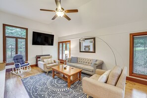 Ein Wohnzimmer mit Deckenventilator, Flachbildfernseher, Sofa, Couchtisch und einem gemusterten Teppich.