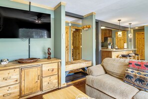 A rustic interior with wooden furniture, a flat-screen TV mounted on the wall, and a cozy seating area with patterned cushions. - Walk to Ski & Main St! Newly Refinished w/ Hot Tub (Breckenridge)