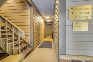 A hallway with a wooden staircase leading to a landing, and signs indicating the building name and floor levels. - Walk to Ski & Main St! Newly Refinished w/ Hot Tub (Breckenridge)