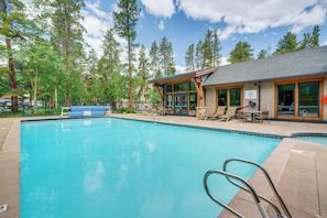 A swimming pool with lounge chairs and a wooden building with large windows. - Walk to Ski & Main St! Newly Refinished w/ Hot Tub (Breckenridge)