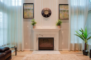 A living room with a fireplace, two potted plants, a clock, and artwork on the walls. - 4 Mi to Dtwn Bel Air & Trails! Grand Home (Bel Air)