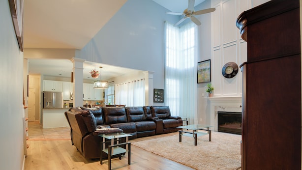 A spacious living room with a leather sofa, a glass coffee table, and a fireplace.