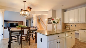 A spacious kitchen with a central island, wooden dining table, and chairs.