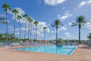 Piscina com espreguiçadeiras e palmeiras.