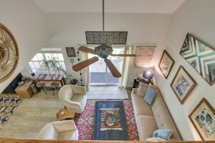 Amplia sala de estar con ventilador de techo, sofá, mesa de centro y comedor con sillas y mesa.