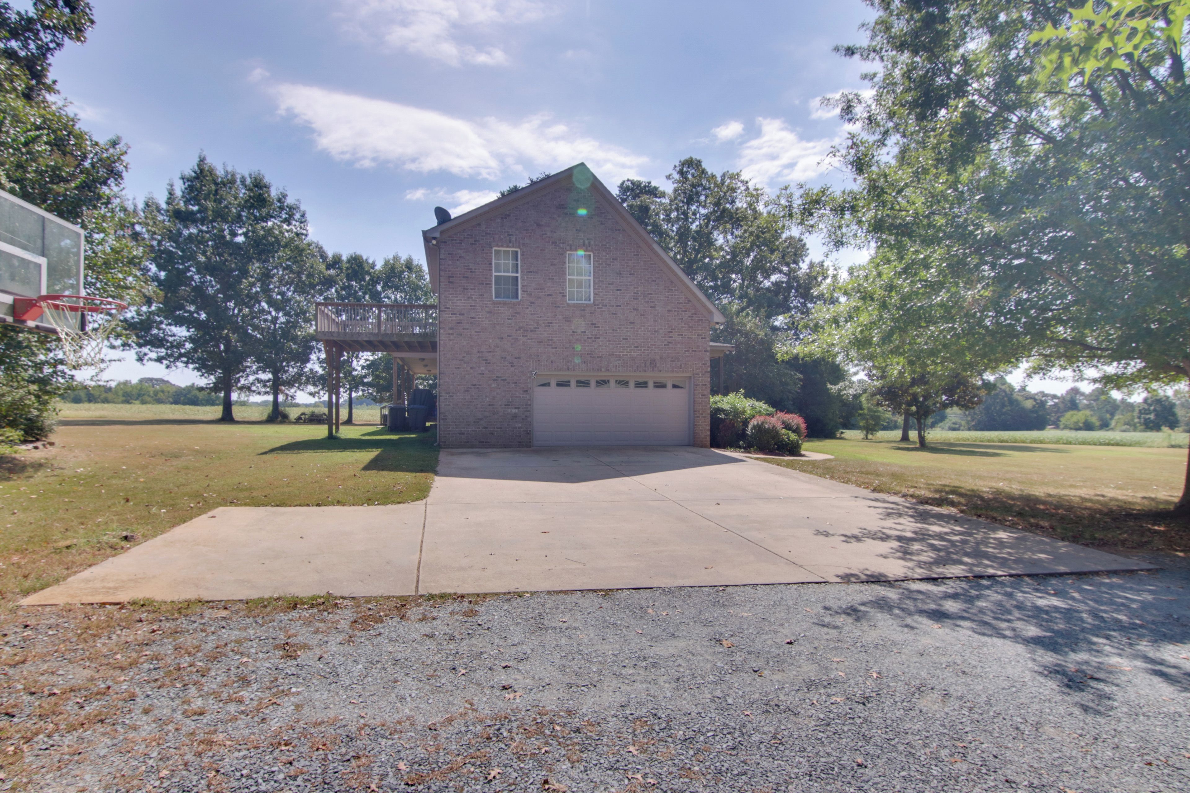 A single-story brick house with a garage, a basketball hoop, and a covered patio area.