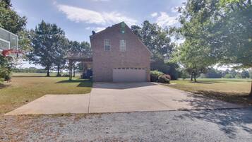 A single-story brick house with a garage, a basketball hoop, and a covered patio area.