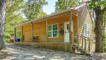 Une cabane en bois avec une véranda, une porte et une fenêtre.