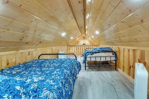 Une petite pièce en bois, avec deux lits, un ventilateur et un radiateur.